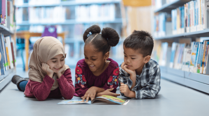Parenting as Social Justice: A Culturally Responsive Columbus Day Three children laying on their bellies reading a book.