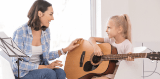 A girl taking a guitar music lesson.