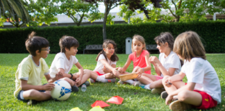Knowing When to Say “When” With Kid Activities Kids sitting in a circle outside with a soccer ball.