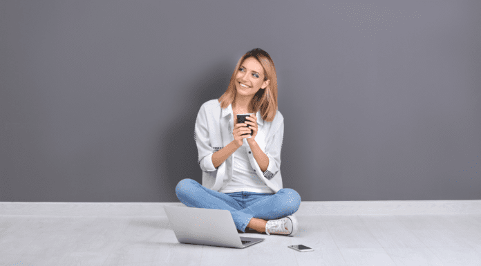 A woman sitting in front of a computer with a coffee.