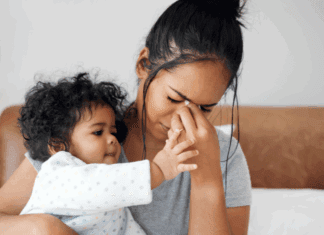 Talk To Me Tomorrow A woman holding her baby while she holds her face.