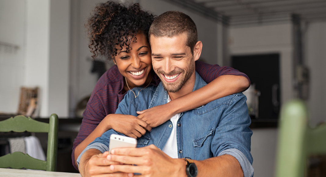 A happy couple looking at a phone. 
