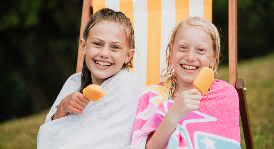 Two girls eating popsicles.
