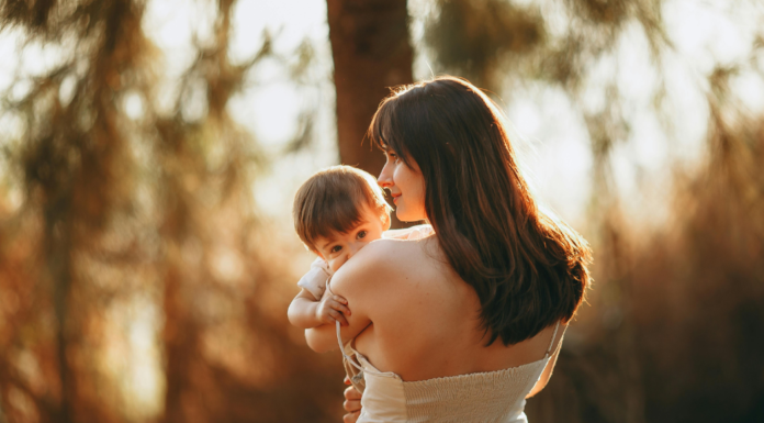 A mom holding her baby in the sunlight.