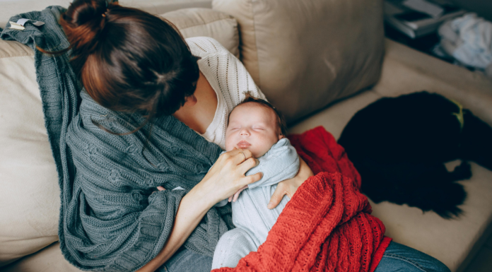 A new mom holding her baby on the couch.