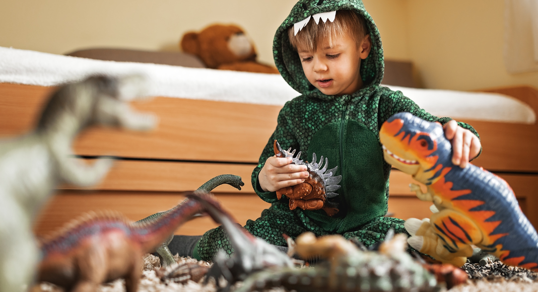 A boy playing with dinosaurs.