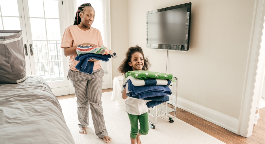 A mom and daughter putting away folded laundry.