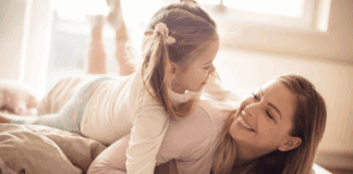 Mom Guilt: Let it Go! A woman laying down with her daughter on top of her smiling.
