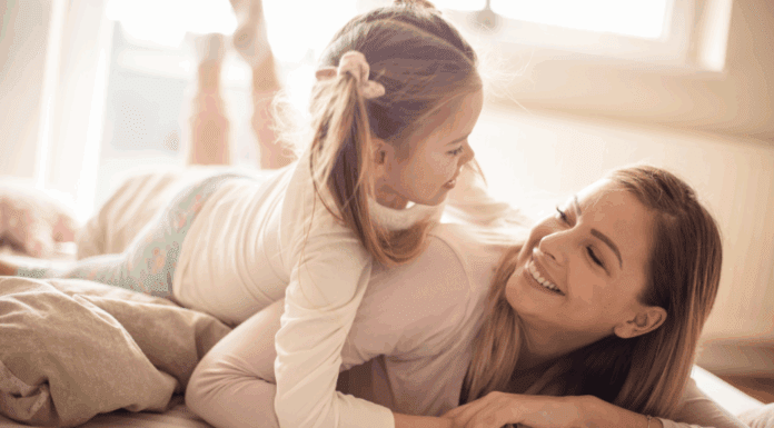 Mom Guilt: Let it Go! A woman laying down with her daughter on top of her smiling.