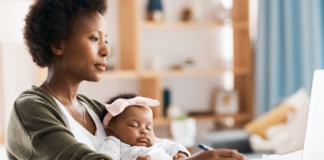 Ditch the Same Old “New Year, New Me” Speech A mom working while holding her baby.