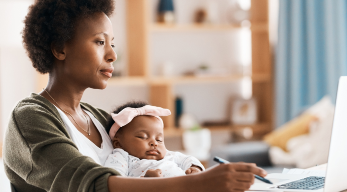 A mom working while holding her baby.