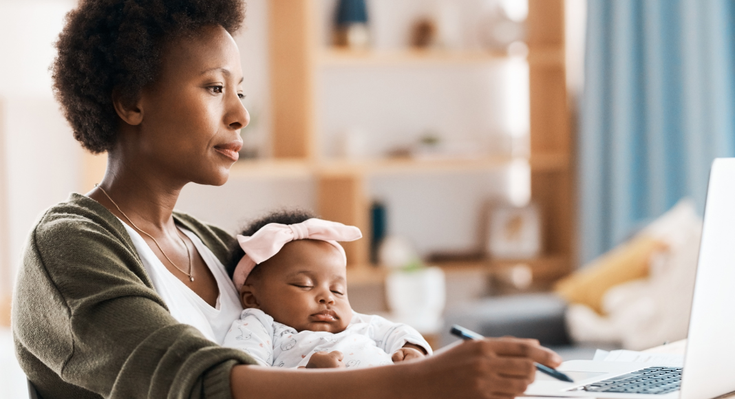 A mom working while holding her baby.