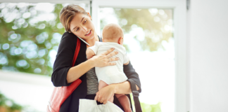 The Pressure to Be Positive A mom on the phone holding her baby and lots of bags.