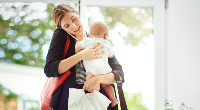 The Pressure to Be Positive A mom on the phone holding her baby and lots of bags.