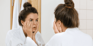 A woman looking in the mirror at her face.