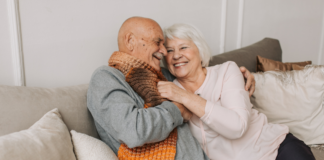 An older couple cuddling on the couch.