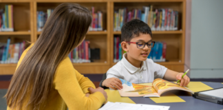 A boy being tutored in the library.