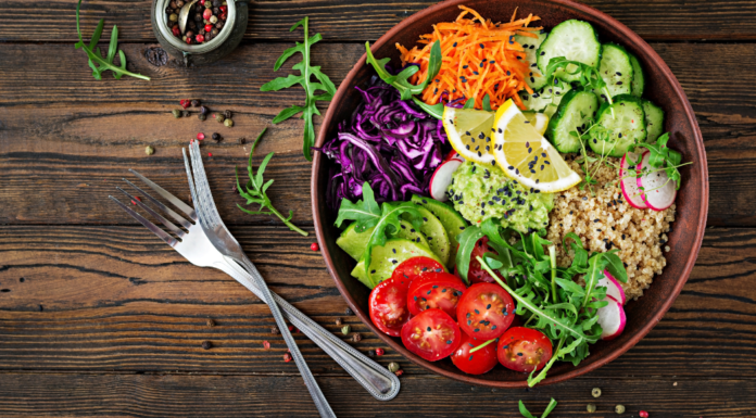 A vegetarian meal in a bowl next to a for and knife.