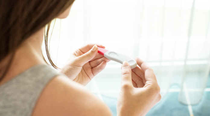A woman holding a pregnancy test.