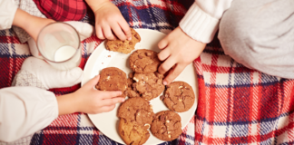 Kids grabbing cookies off of a plate.