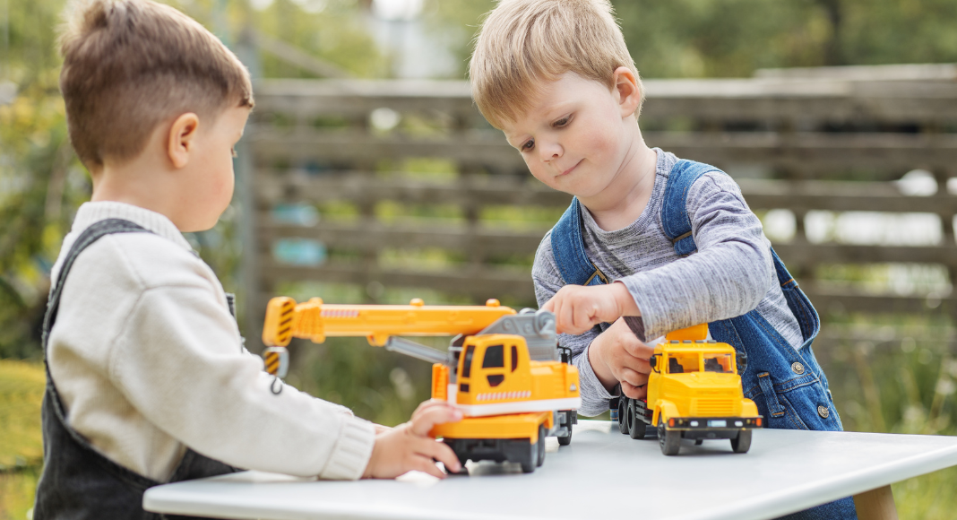 Boys playing outside with trucks.