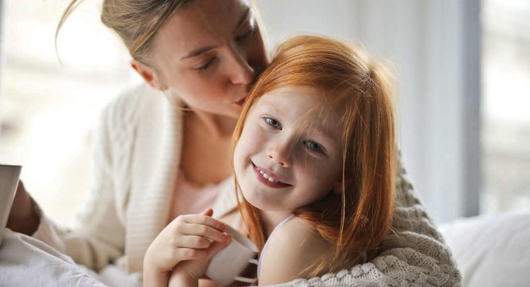 A mom kissing her daughter's head.