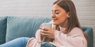 Moms – Give Yourself a Random Act of Kindness A woman sitting on the couch drinking coffee.