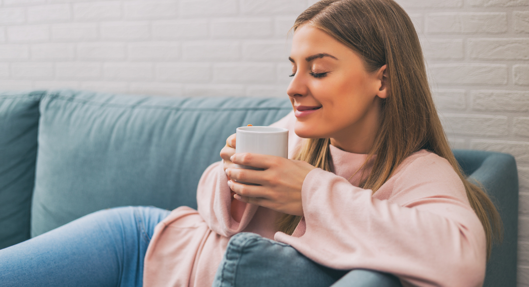 A woman sitting on the couch drinking coffee.