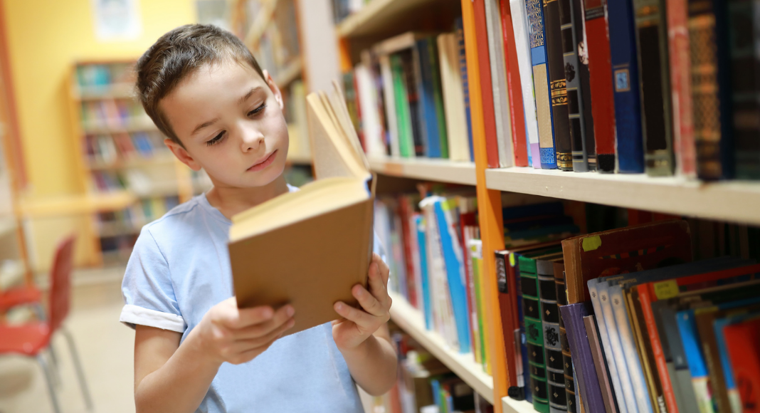 A boy reading a book in the library.