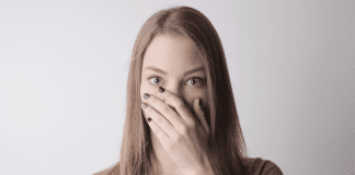 A quiet woman covering her mouth with her hand.