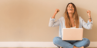 A woman cheering on a computer.