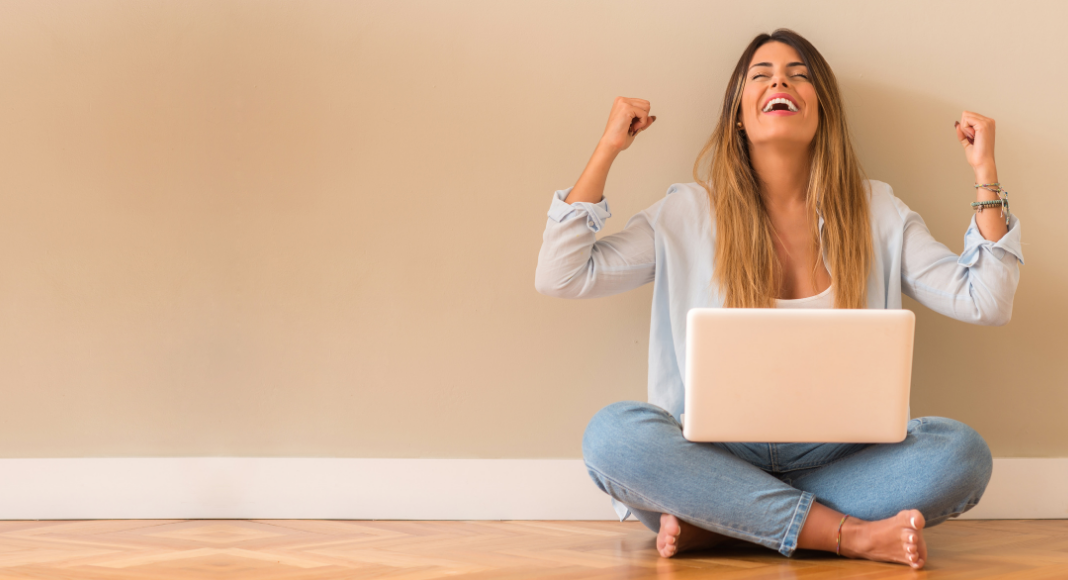 A woman cheering on a computer.
