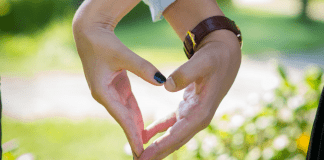 Holding hands in the shape of heart.