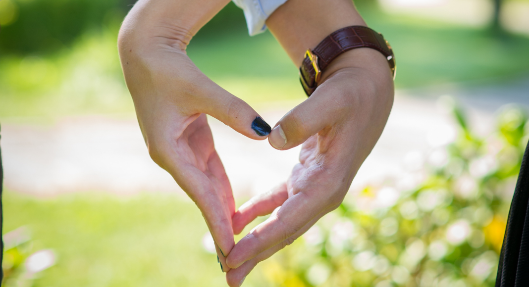Holding hands in the shape of heart.