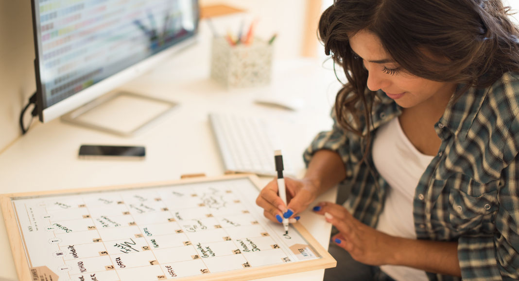 A woman recording events on a calendar. 