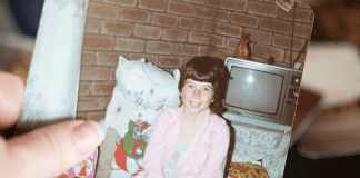 Holding a photo from 1980s.