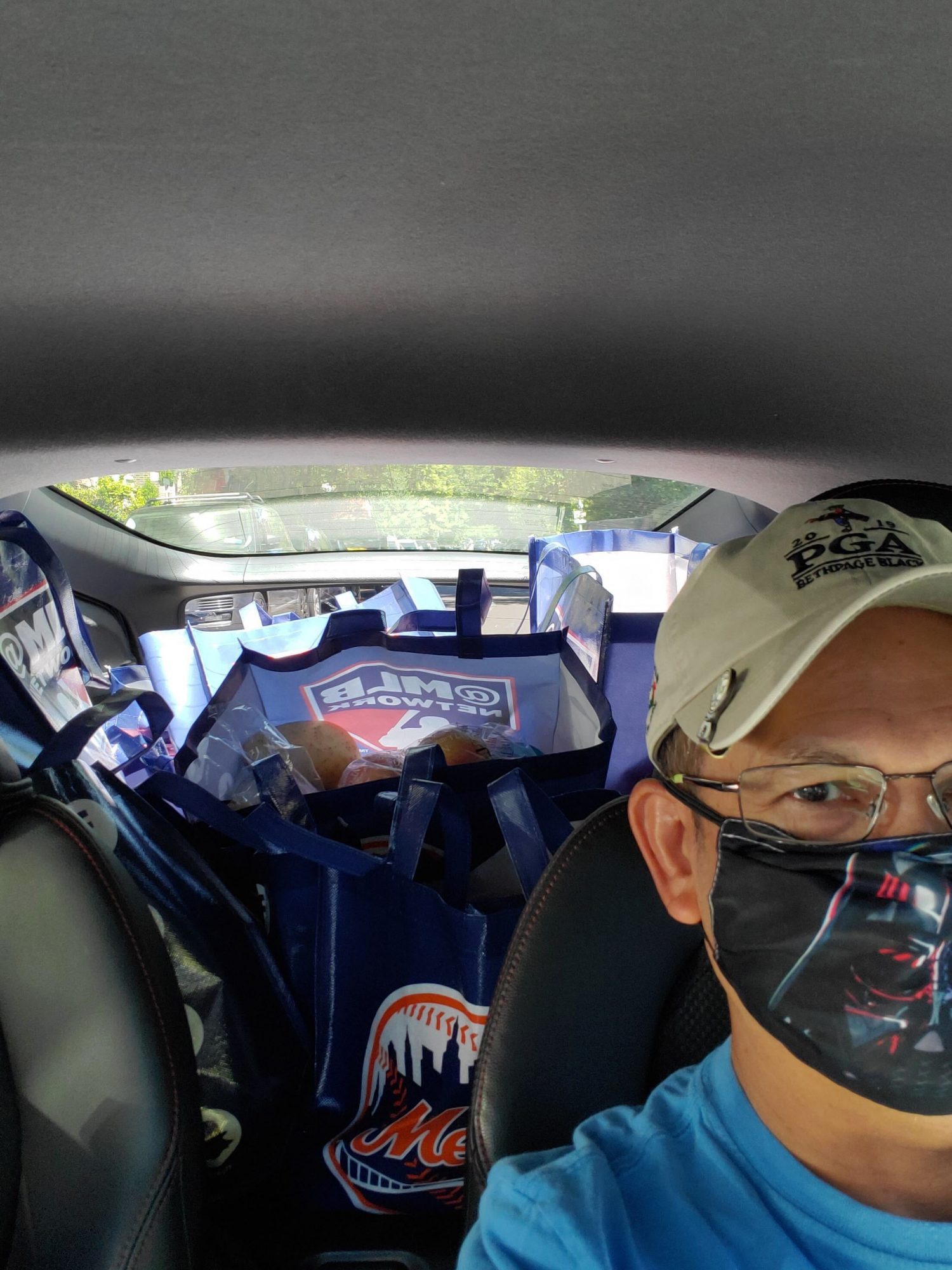 A man driving a car full of groceries.