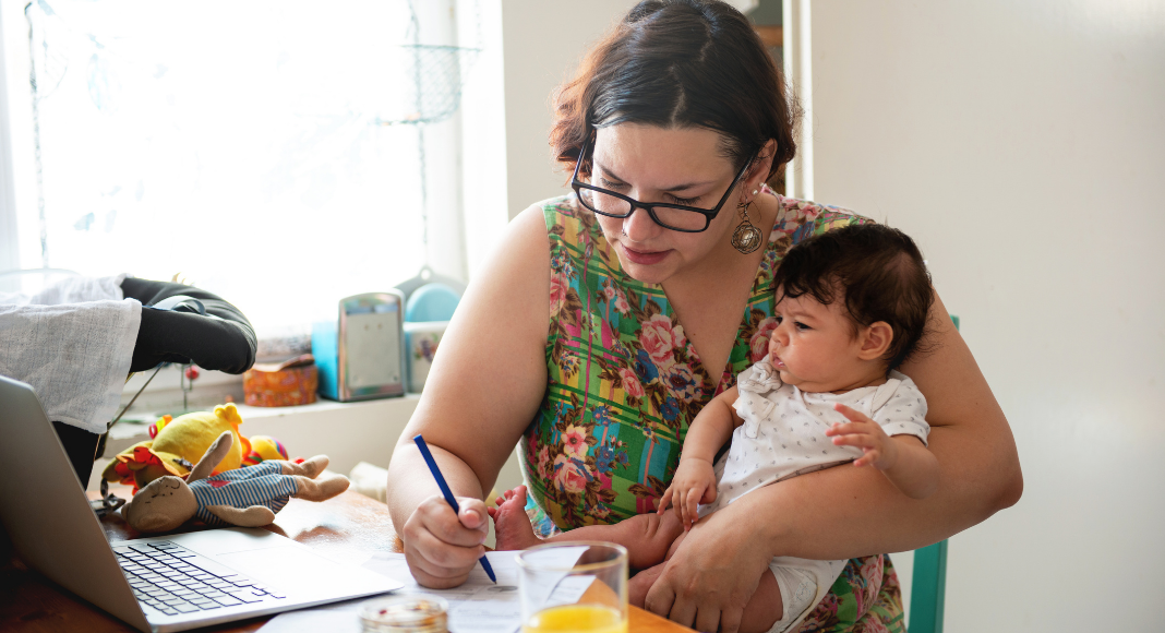 A working mom holding a baby.