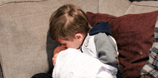 A big brother kissing his baby sister.