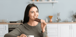 A woman eating chocolate and drinking coffee.