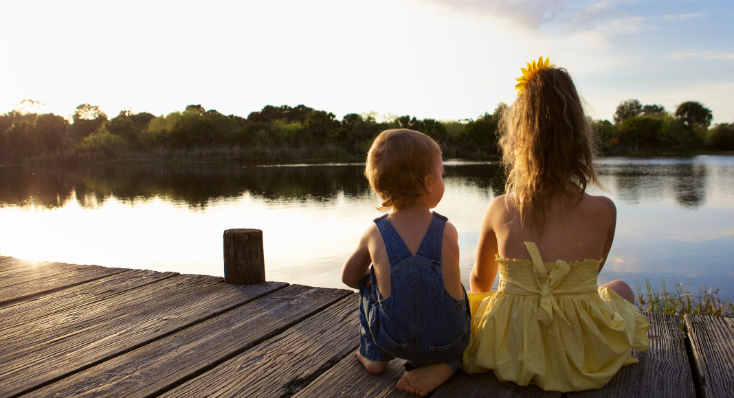 Siblings sitting on a dock. 