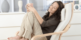 A woman relaxing in a chair drinking coffee.