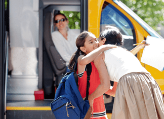 A mom hugging her daughter before she gets on the school bus.