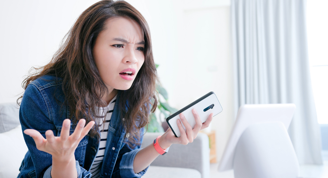 A frustrated woman holding a phone. 