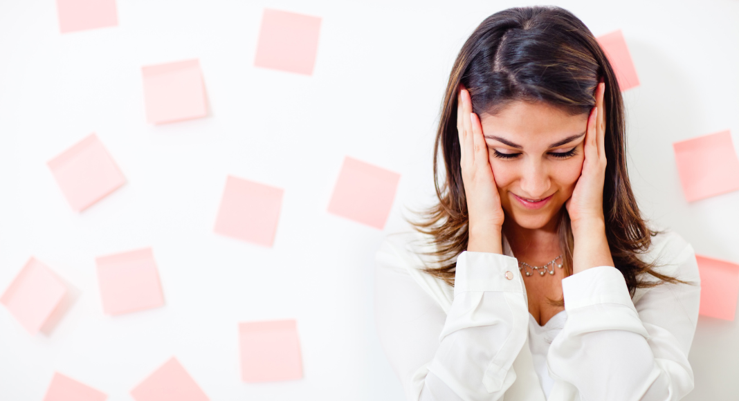 A woman holding her ears on overload.