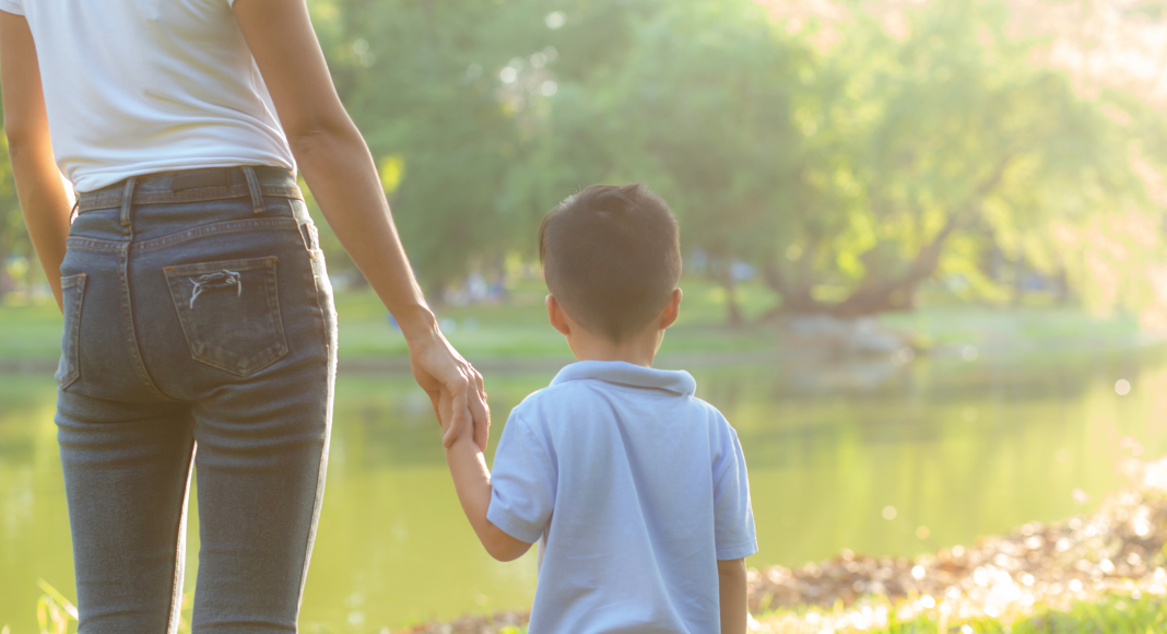 A mother holding her son's hands.
