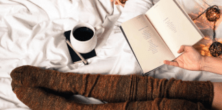 Self-Care During the Holiday Season Resting in bed with a book and coffee.