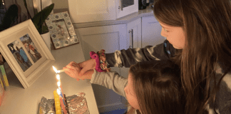 Girls lighting an menorah.