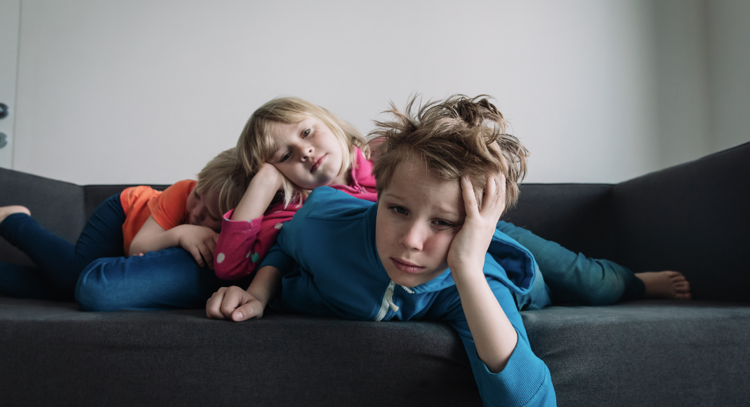 Bored kids laying on the couch.
