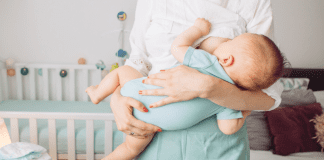 At Last A woman breastfeeding a baby while standing.